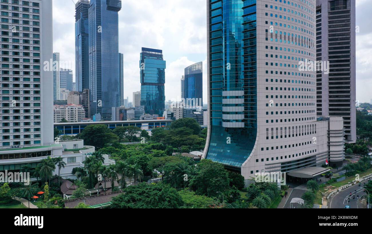 Vista aerea di un moderno ed alto edificio in vetro blu nel quartiere degli affari della citta' di Giacarta. Circondato da alti edifici nella citta' di Giacarta al mattino Foto Stock