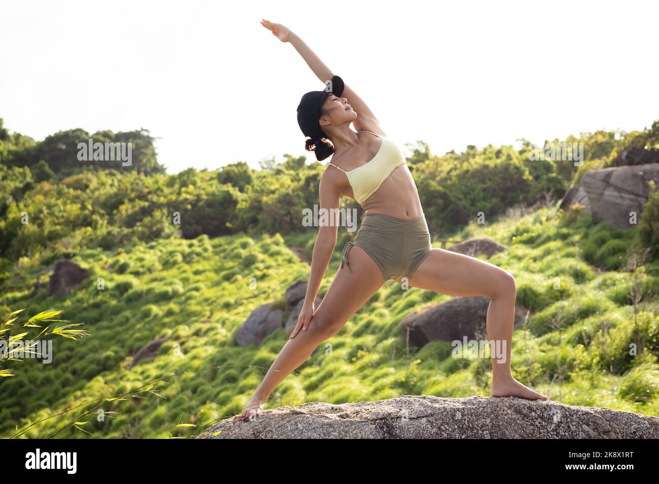 Giovane donna asiatica che pratica yoga sulla cima della montagna. Bella femmina che si allenano all'aperto nella natura Foto Stock