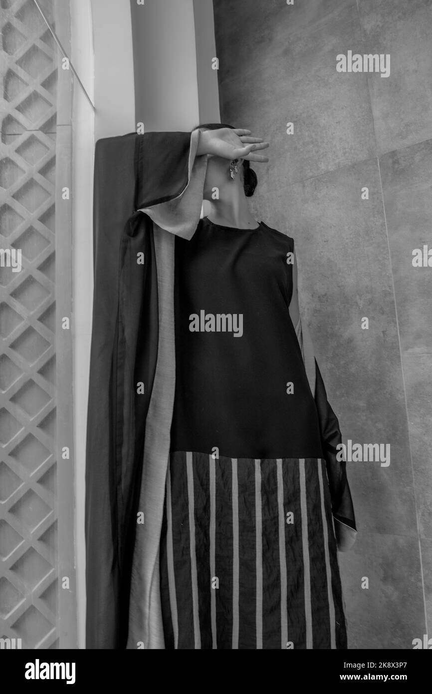 Ragazza giovane in abaya tradizionale araba in bianco e nero, senza volto Foto Stock