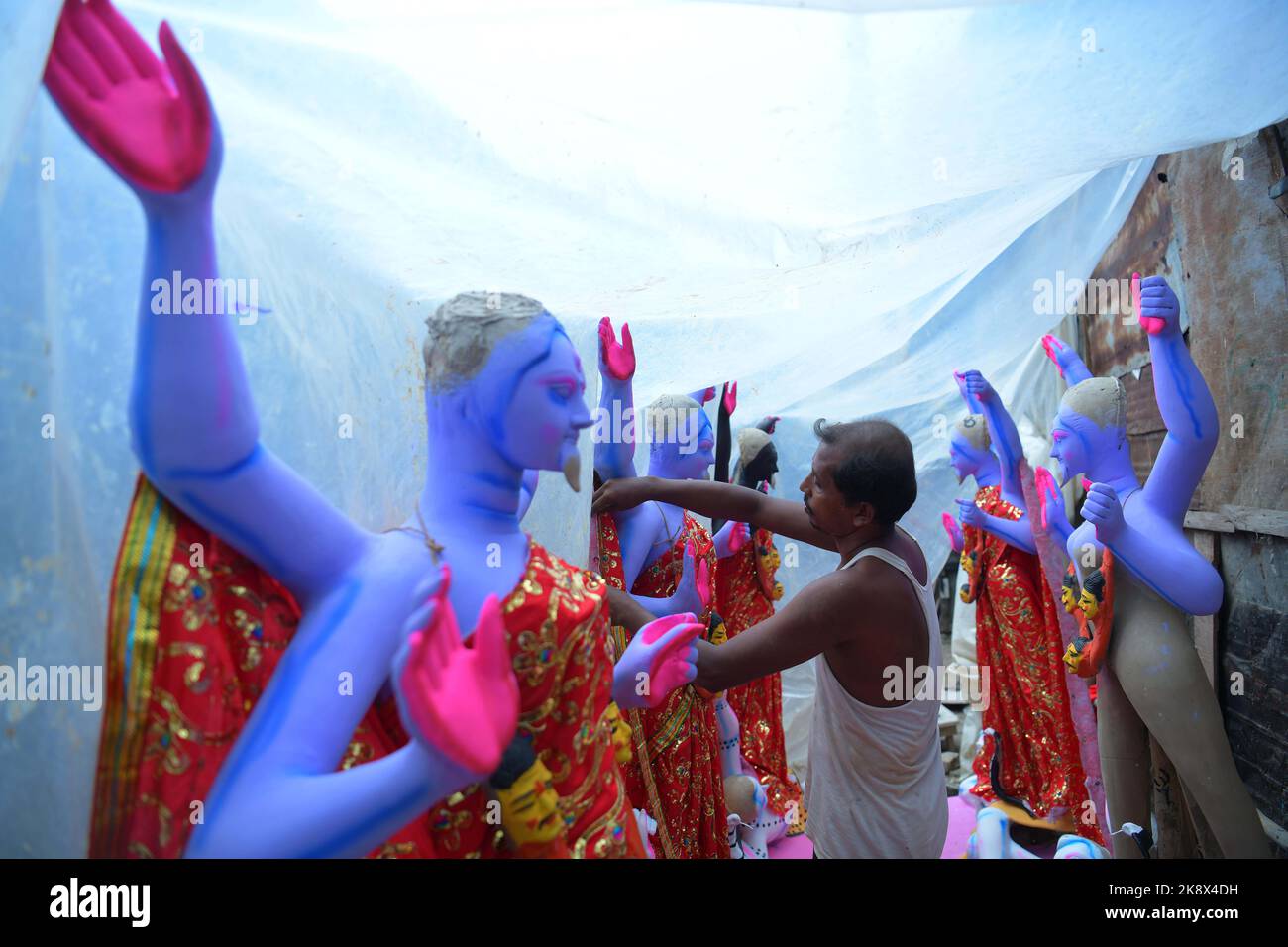 Un artigiano che fa il tocco finale ad un idolo di argilla semi-finito della dea indù Kali, 'la dea del potere', in uno studio ad Agartala. Il culto di Kali si svolge insieme a 'Diwali', il festival delle luci, che sarà celebrato simultaneamente in altre parti del paese, segnando la vittoria sul male e commemorando il tempo in cui il Dio indù Signore Rama ha ottenuto la vittoria su Ravana e ritornato al suo regno Ayodhya. Tripura, India. Foto Stock