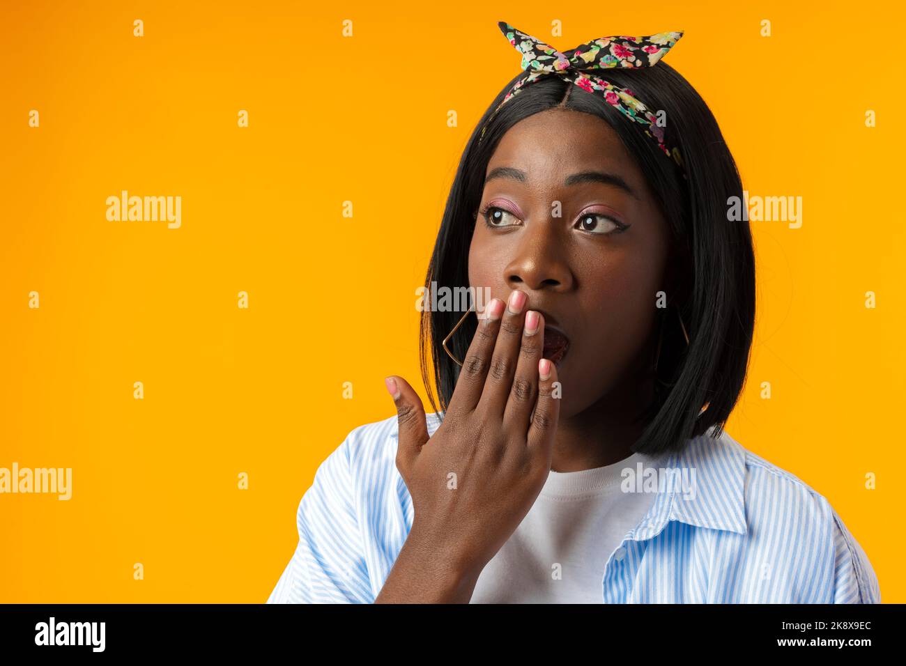 Stordito africano femmina con bocca aperta realizza cattive notizie su sfondo giallo Foto Stock