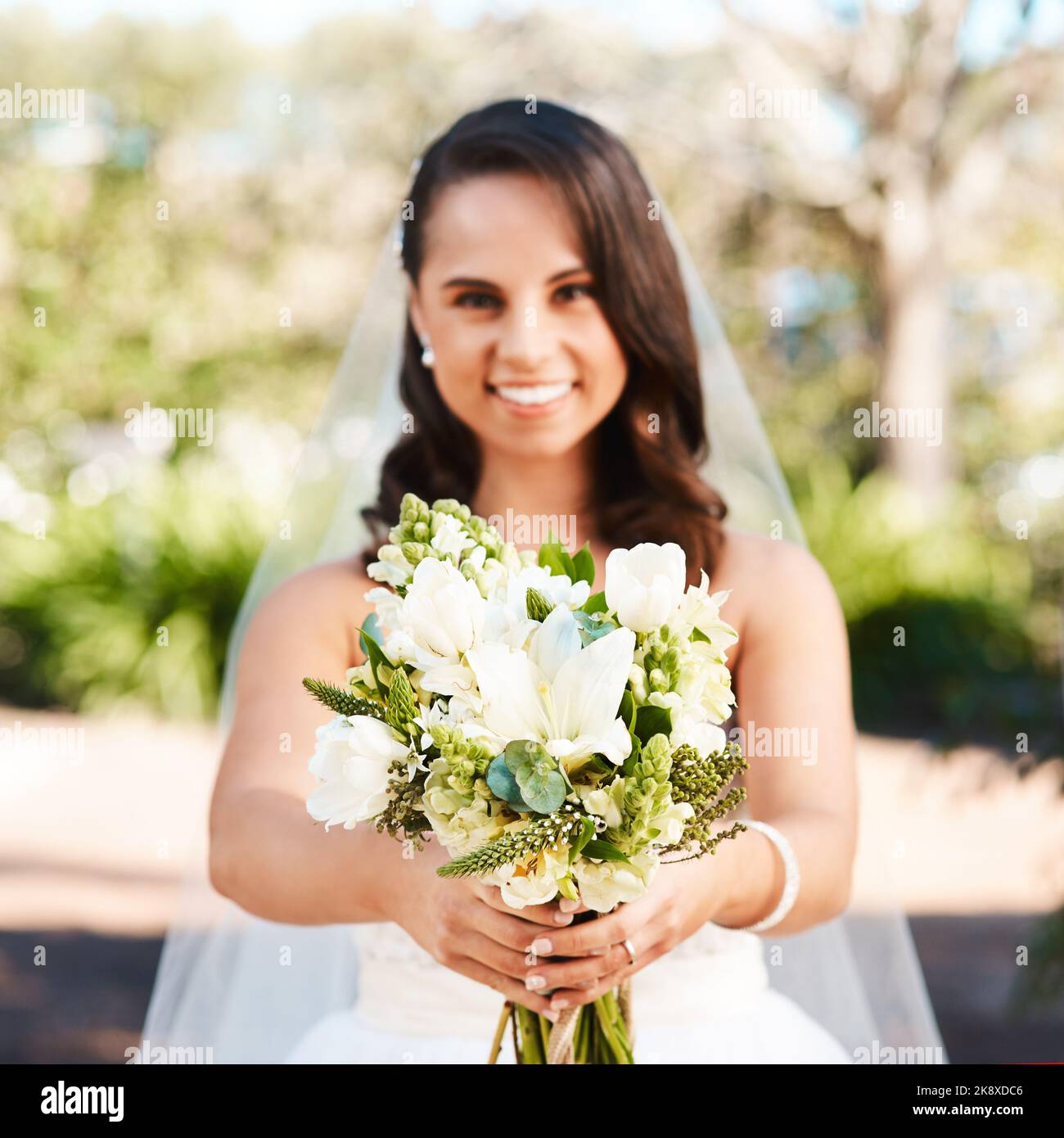 Quanto sono belli questi. Ritratto corto di una bella giovane sposa sorridente mentre tiene un bouquet di fiori il suo giorno di nozze. Foto Stock