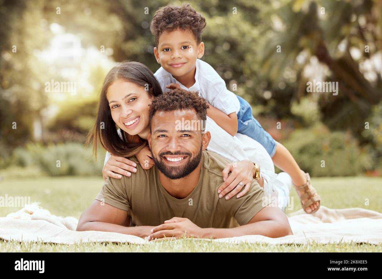 Relax, sorriso e pic-nic con ritratto di famiglia nel parco per l'estate, felice e la natura. Benessere, primavera e salute con gli altri e il padre abbracciare con Foto Stock