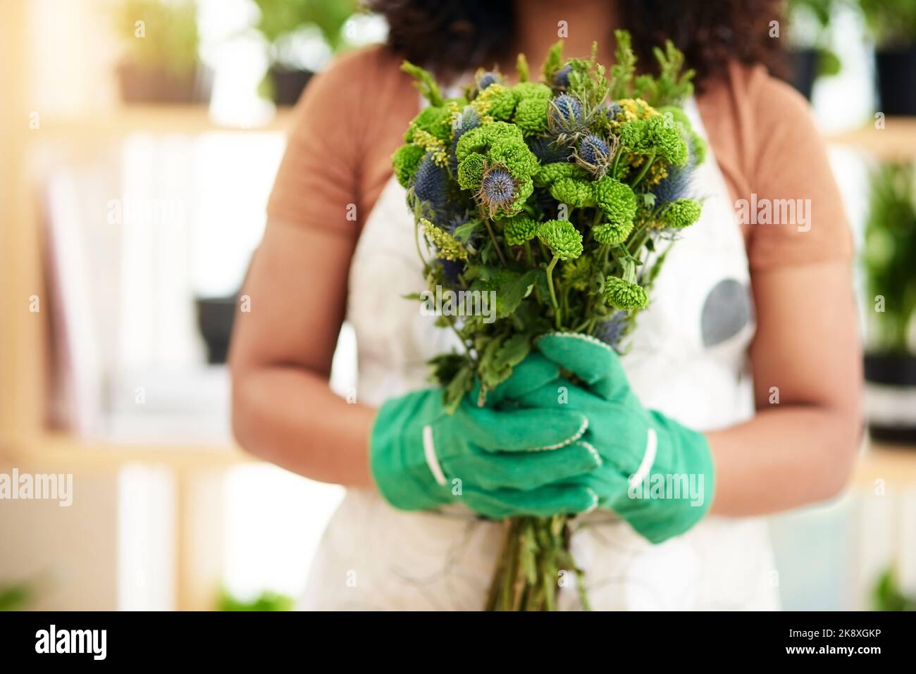 Pronto per il ritiro. Una giovane e irriconoscibile botanica femminile che tiene un bouquet di fiori mentre lavora nel suo fiorista. Foto Stock