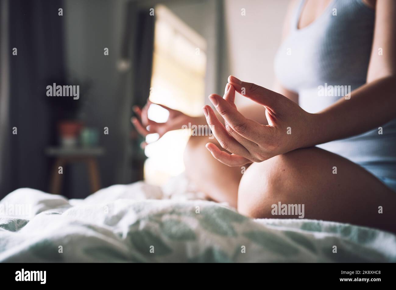 E' necessaria la pace interiore, una donna irriconoscibile che medita mentre si siede sul letto nella sua camera da letto a casa. Foto Stock