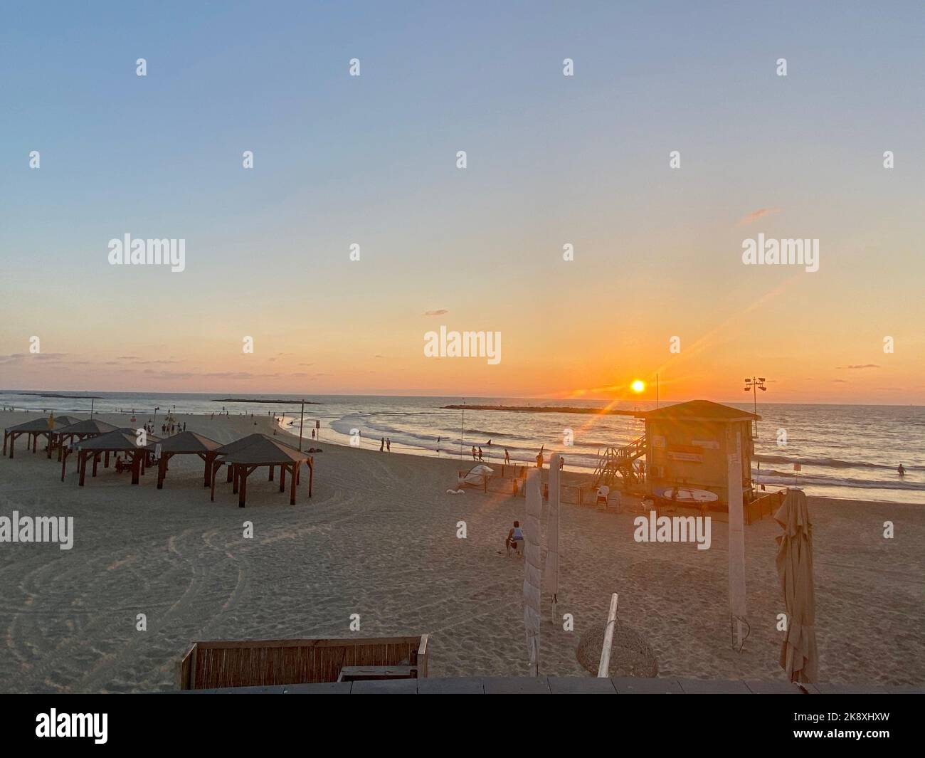 La gente in vacanza a piedi lungo la spiaggia di sabbia al tramonto Foto Stock