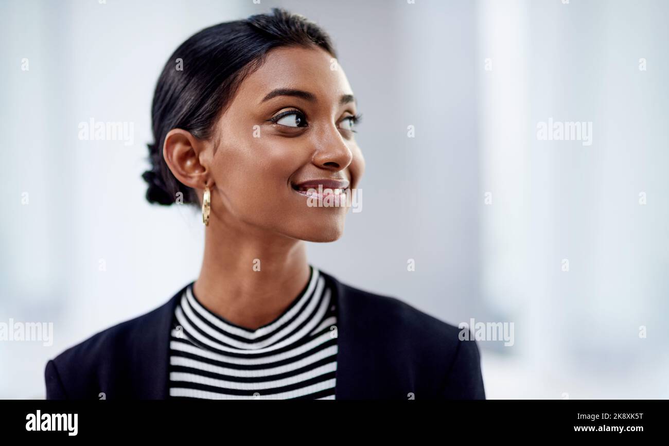 Finalmente tutto sta cadendo sul posto. Una giovane donna d'affari attraente che guarda premurosa e fiduciosa all'interno del suo ufficio sul lavoro. Foto Stock