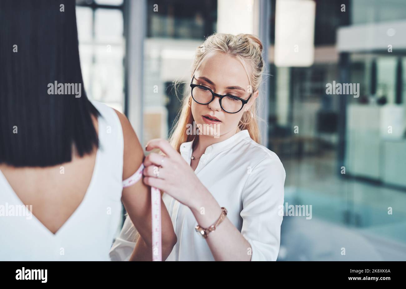 Il design è tutto sui dettagli. Un designer di moda che prende le misure dei suoi clienti nel suo workshop. Foto Stock