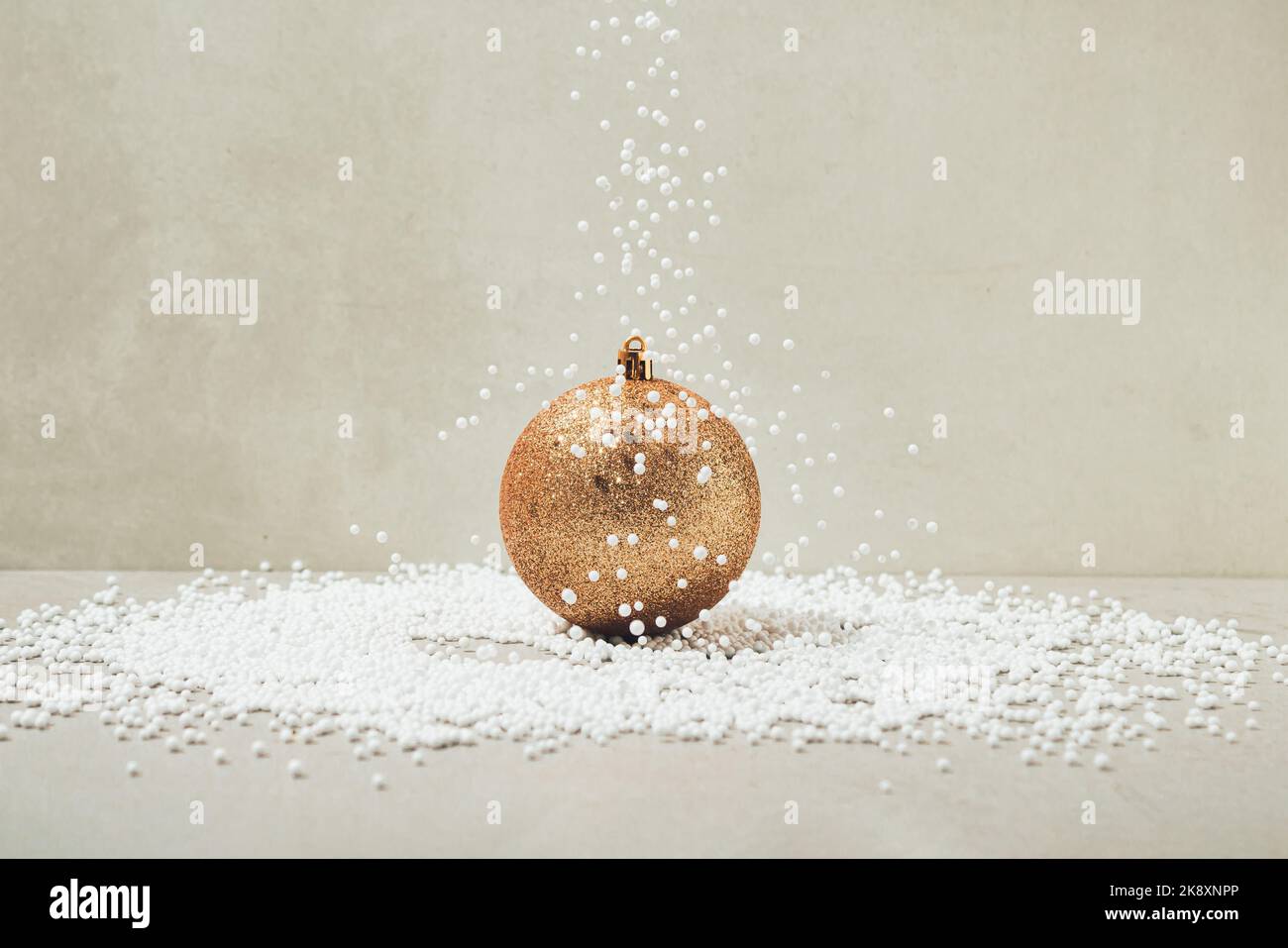 Neve artificiale che cade su oro colorato brillante Natale baule. Concetto minimo di saluto per le feste. Foto Stock