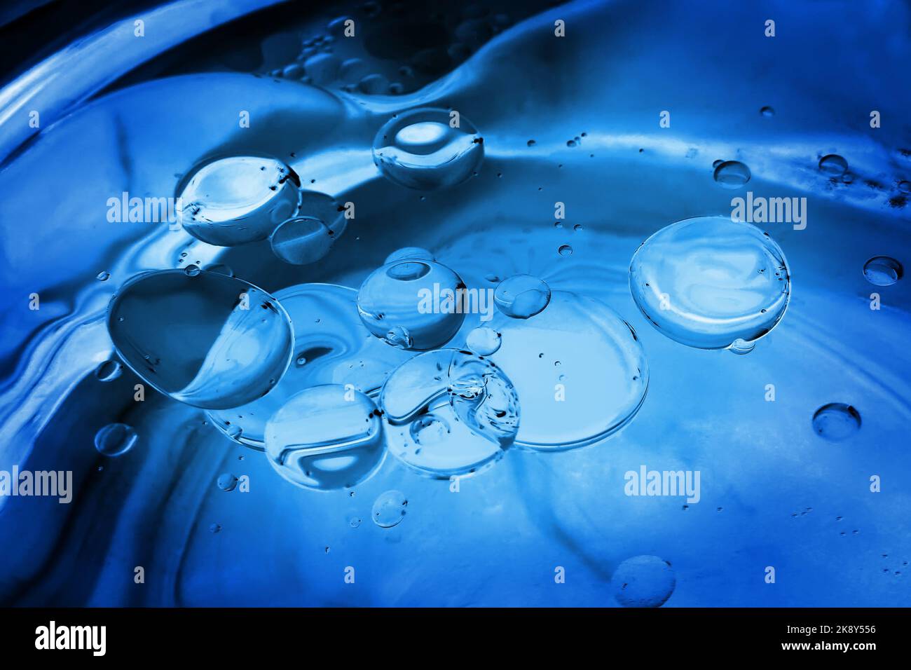 Closeup di goccioline di olio in acqua, tondo in blu. Sfondo astratto. Foto Stock