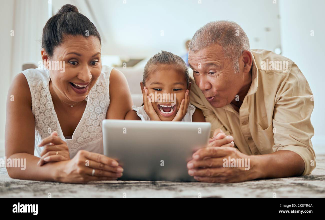 Rilassatevi, tablet digitale e famiglia sul pavimento nel soggiorno, stupendo e felice con cartoni animati o animazioni online in Messico. Famiglia felice, nonni e. Foto Stock