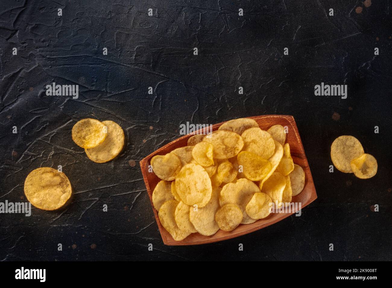 Patatine o patatine fritte, uno spuntino, sparato dall'alto su uno sfondo scuro con un posto per il testo Foto Stock