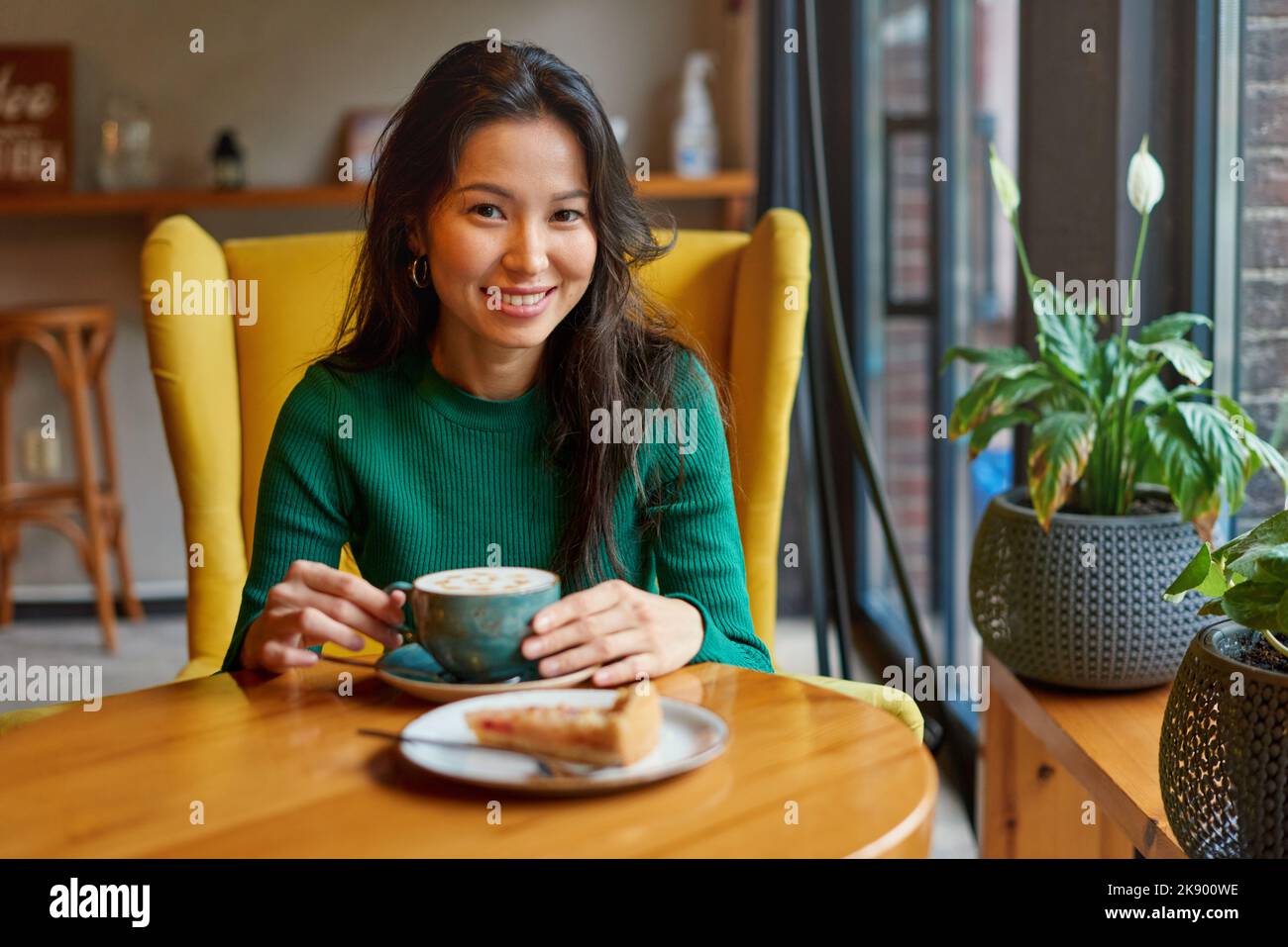 Ritratto di giovane donna asiatica che beve caffè con torta di mele in caffè Foto Stock