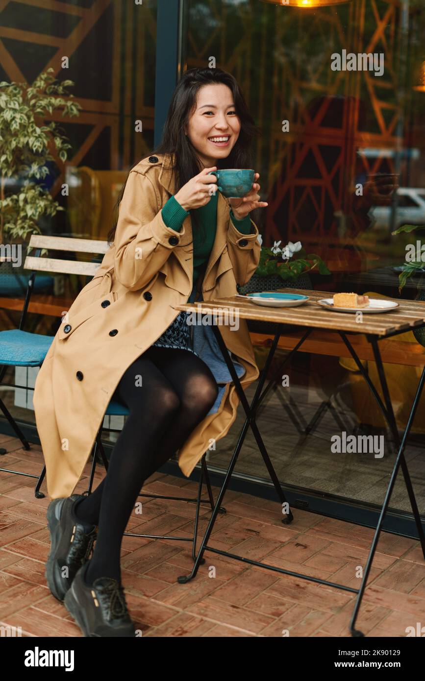 Ritratto di giovane donna asiatica attraente bere caffè witn torta di mele in caffè sulla terrazza del caffè Foto Stock