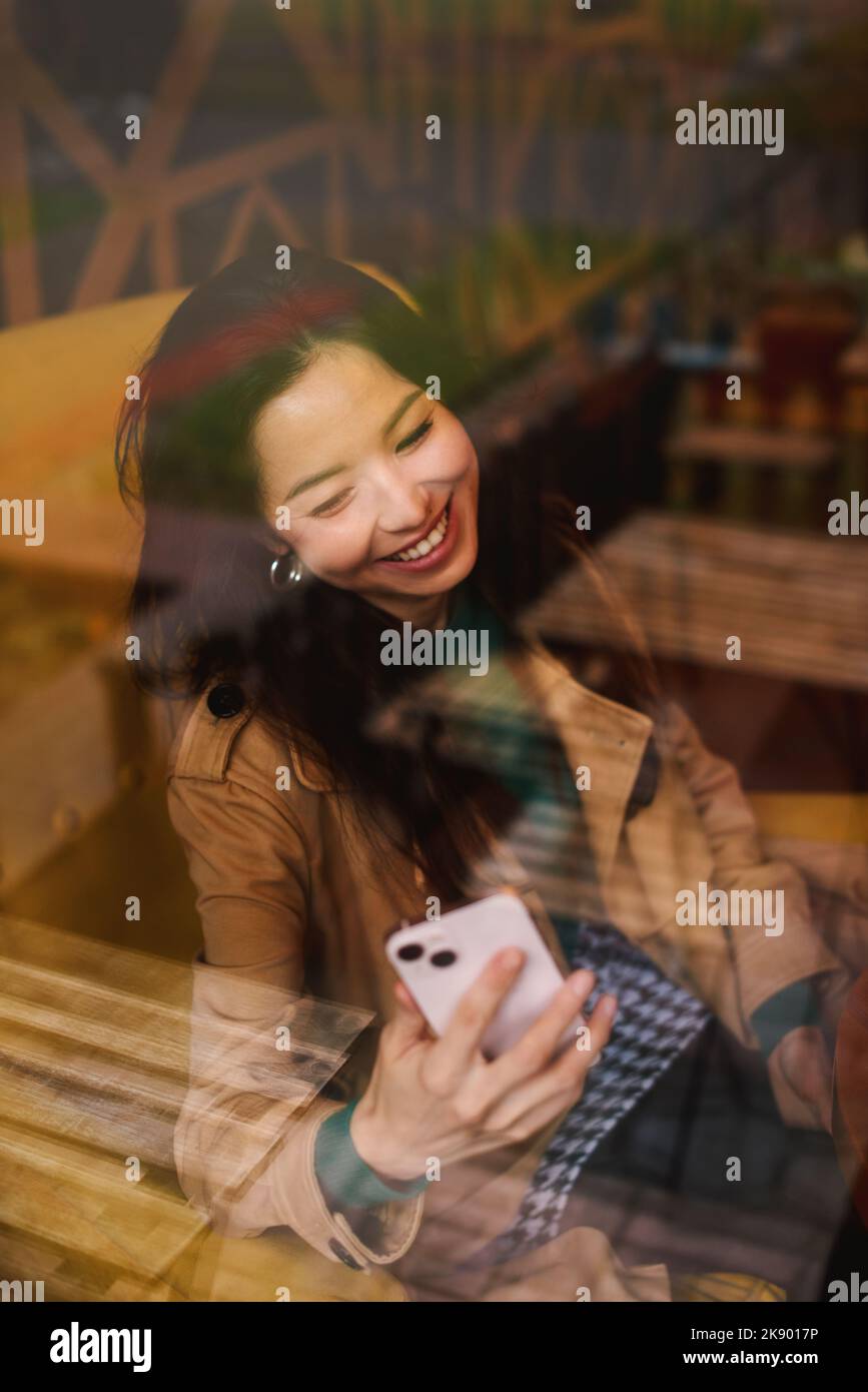 Guardando attraverso la finestra. Ritratto di giovane donna asiatica che prende selfie in caffè Foto Stock