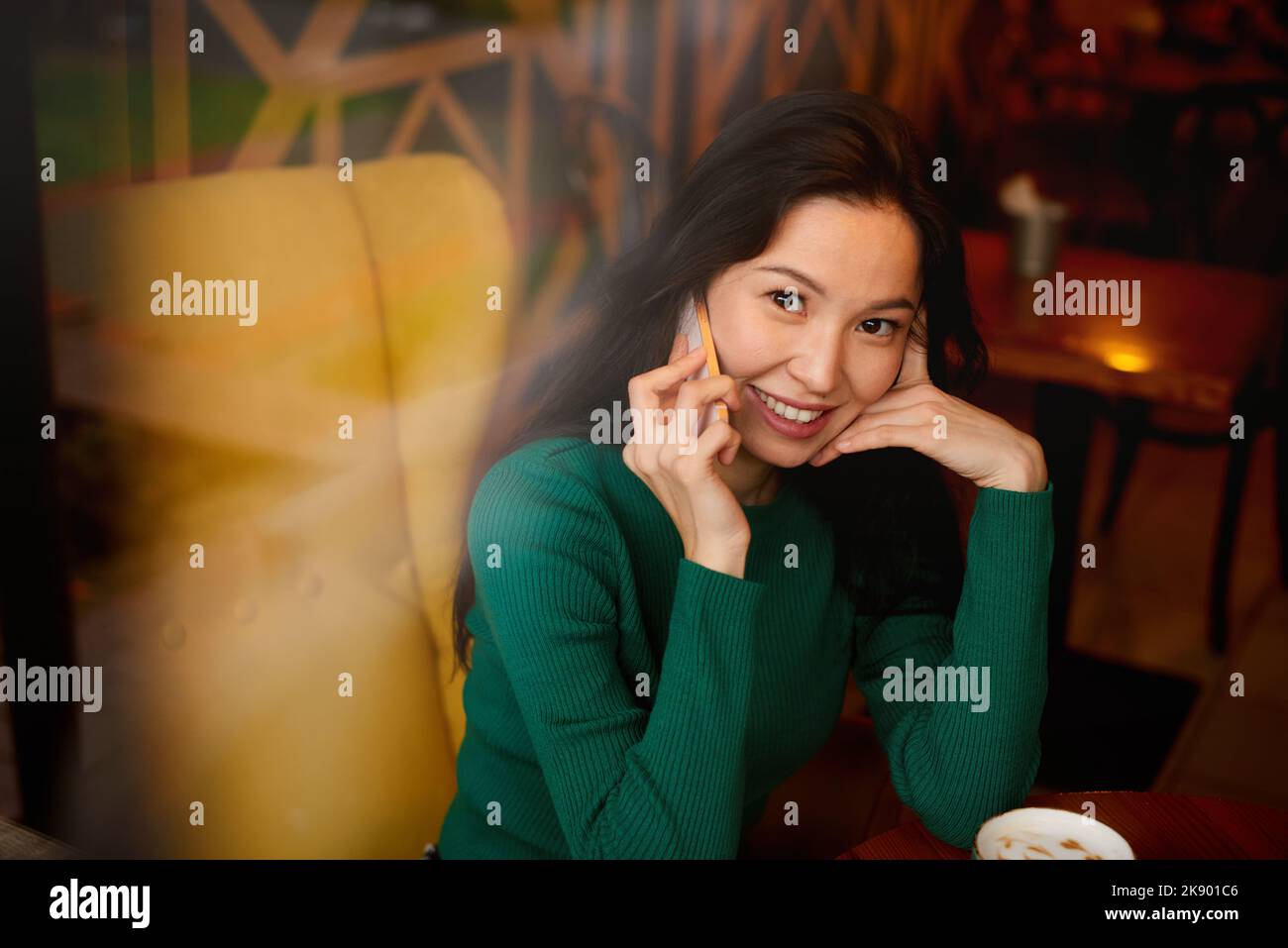 Ritratto giovane donna asiatica kazaka guardando nella fotocamera parlare, comunicando sul telefono cellulare Foto Stock