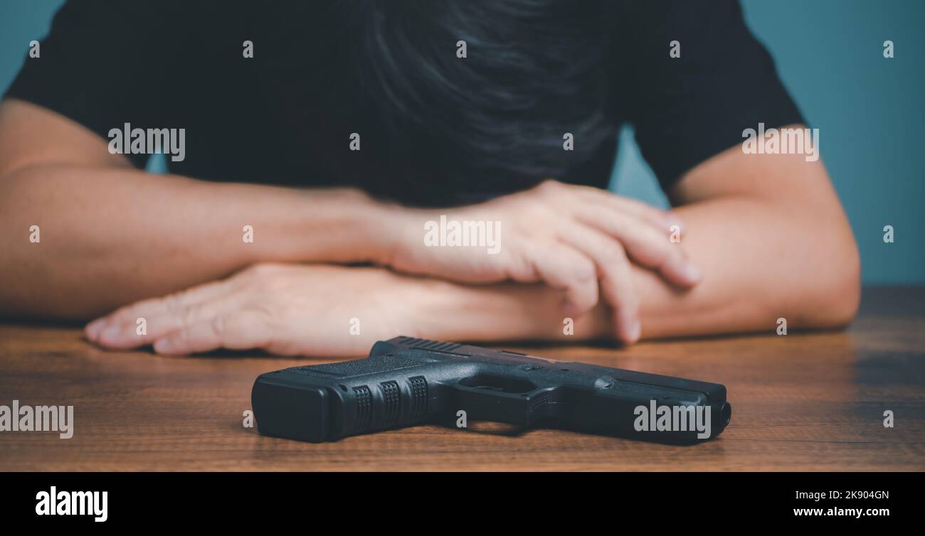 Uomo d'affari triste e depresso con la pistola sulla scrivania. Foto Stock