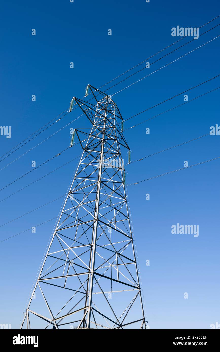 Una torre di trasmissione a traliccio o traliccio che porta 132kv cavi elettrici contro un cielo blu chiaro. Foto Stock