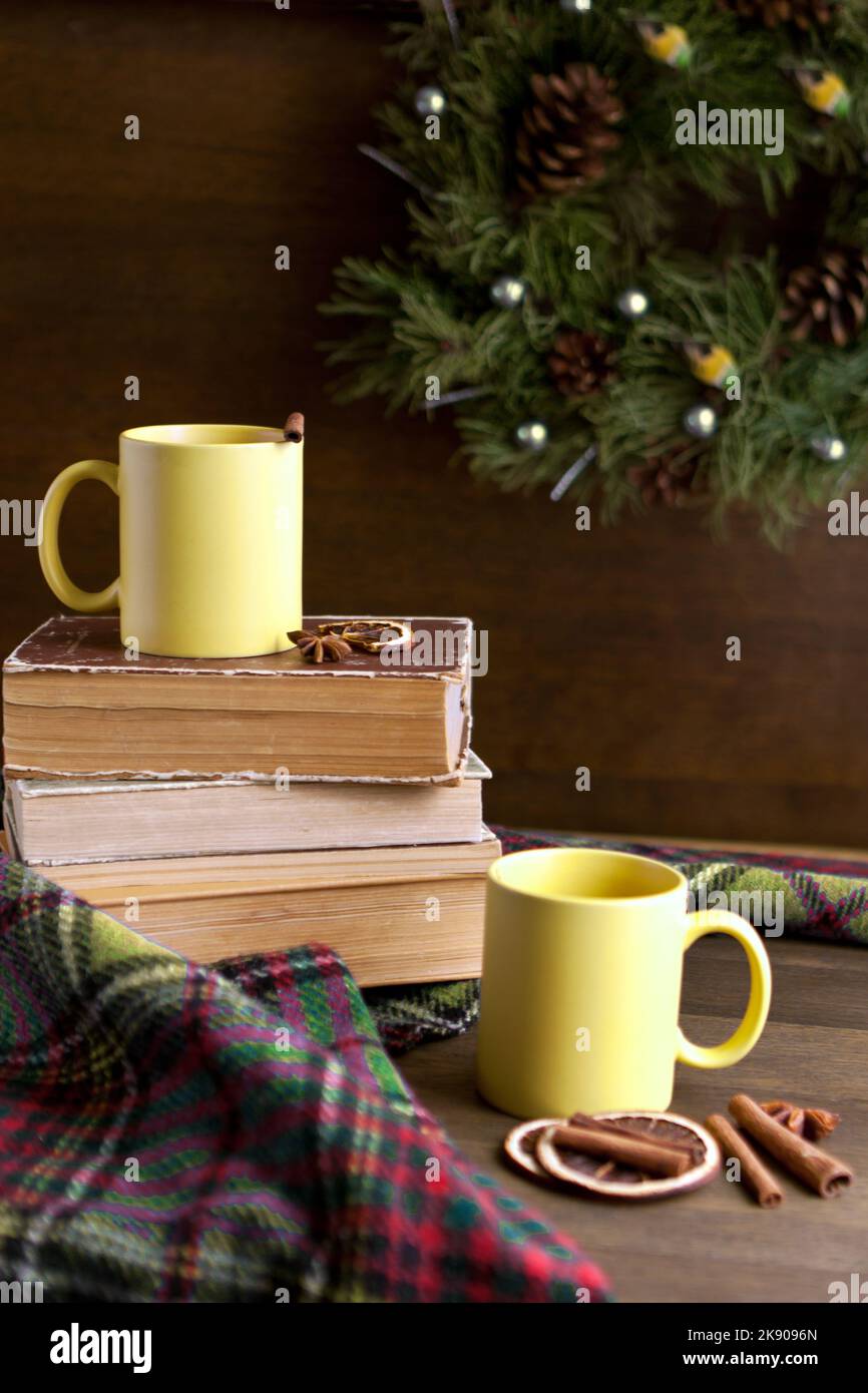 libri e due coppe gialle vicino alla corona con cannella vicino alle decorazioni natalizie su tavola di legno Foto Stock