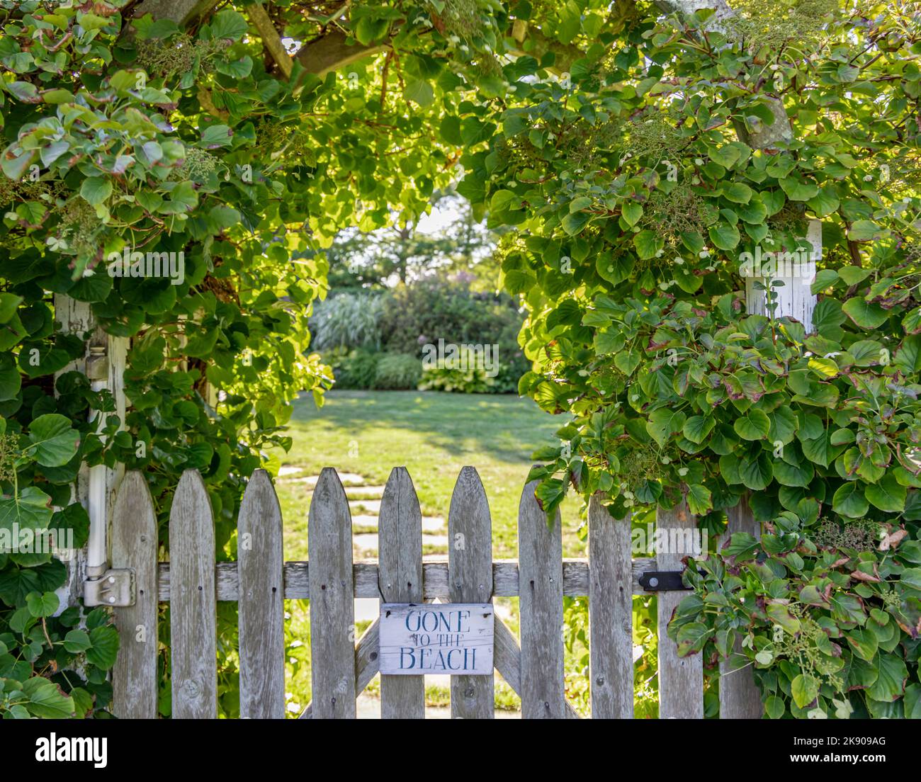 Un vecchio cancello e un ingresso ad arco con un cartello che dice "Gone to the Beach" Foto Stock