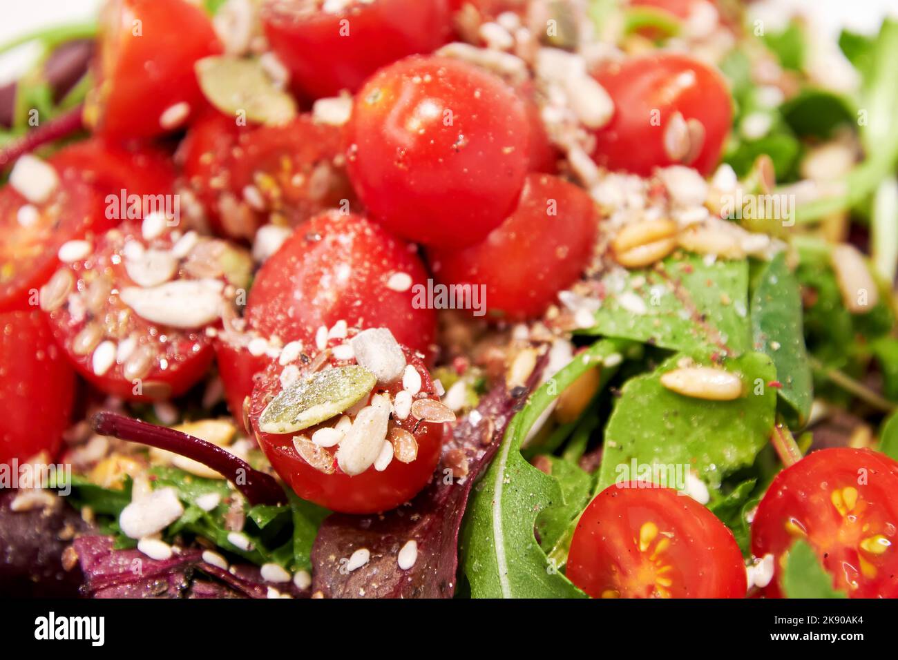 Insalata di verdure con pomodori, lattuga verde, semi e olio, sale, pepe. Texture di fondo del cibo Foto Stock