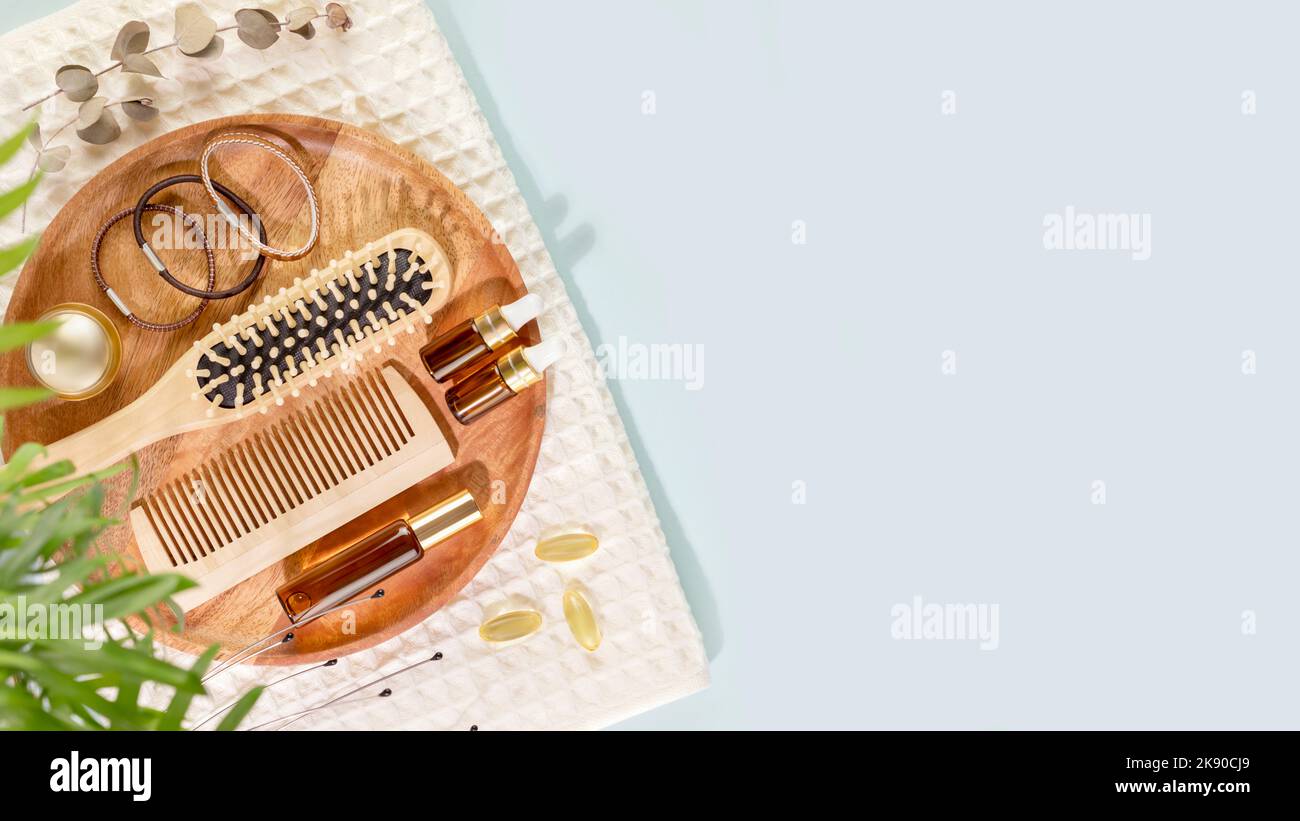Set per la cura dei capelli su un piatto di legno con asciugamano bianco e spazio copia Foto Stock