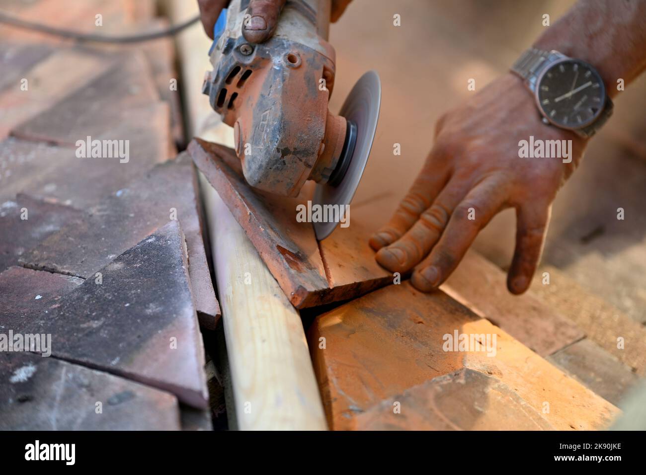 Lavori di copertura su tetto residenziale coperto di tegole di argilla, il taglio di tegole di argilla con smerigliatrice angolare per il montaggio di taglio angolare su travi di anca Foto Stock