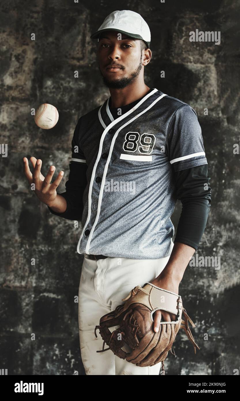 Baseball, sport e uniforme con un atleta uomo su uno sfondo scuro indossando un mitt mentre tiene una palla. Ritratto, sport e fiducioso con un maschio Foto Stock