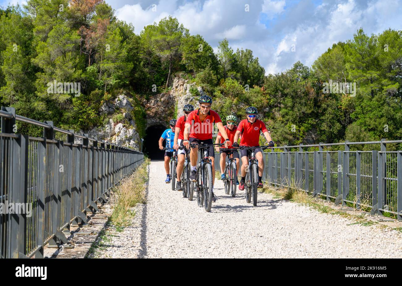 Un gruppo di ciclisti norvegesi di mezza età che attraversano un ponte sulla ferrovia da Spoleto a Norcia in disuso a noleggio. Umbria, Italia. Foto Stock