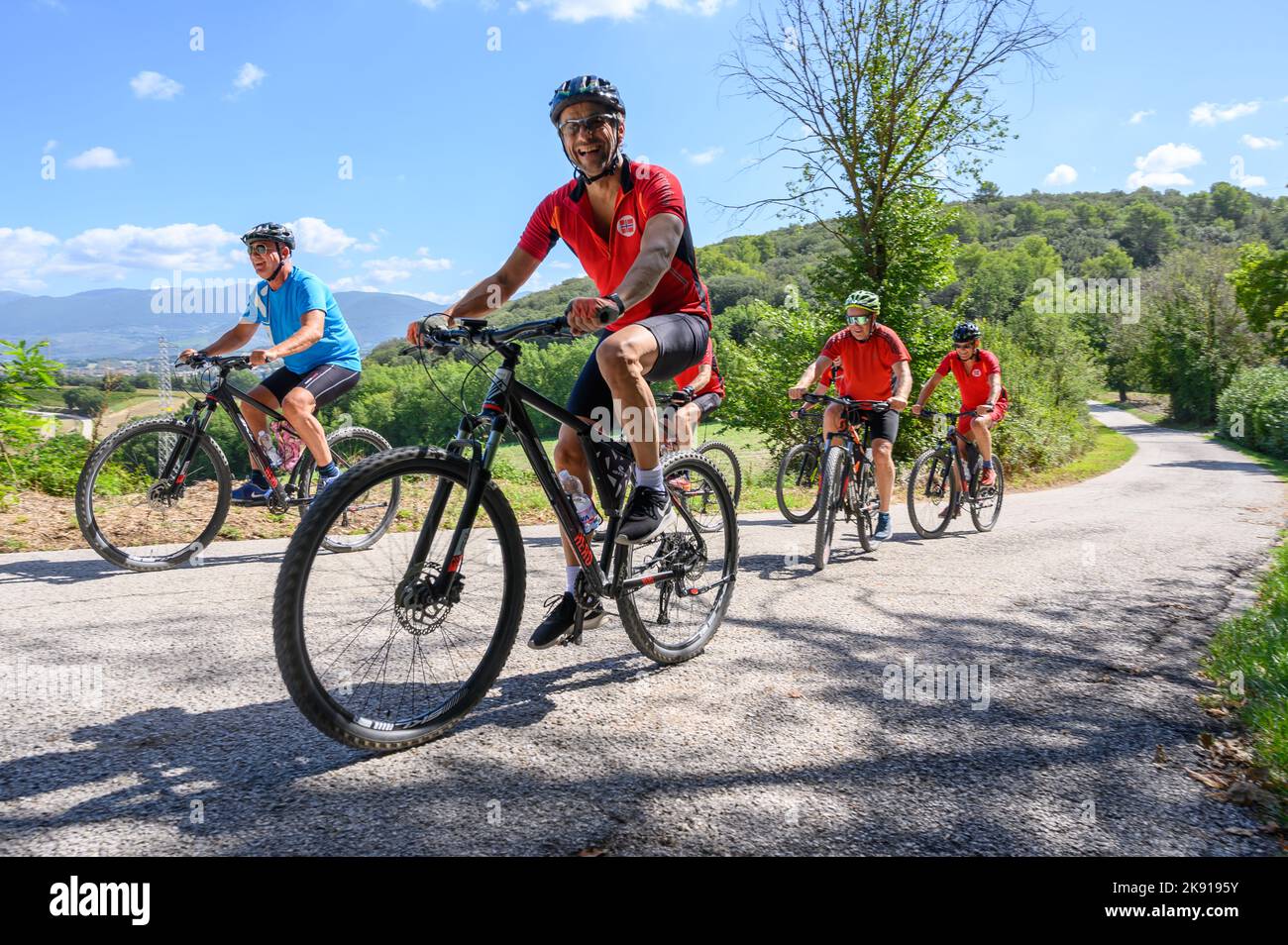 Un gruppo di ciclisti norvegesi di mezza età in bicicletta noleggiata percorrendo una strada collinare nel paesaggio umbro vicino a Spoleto, Umbria, Italia. Foto Stock