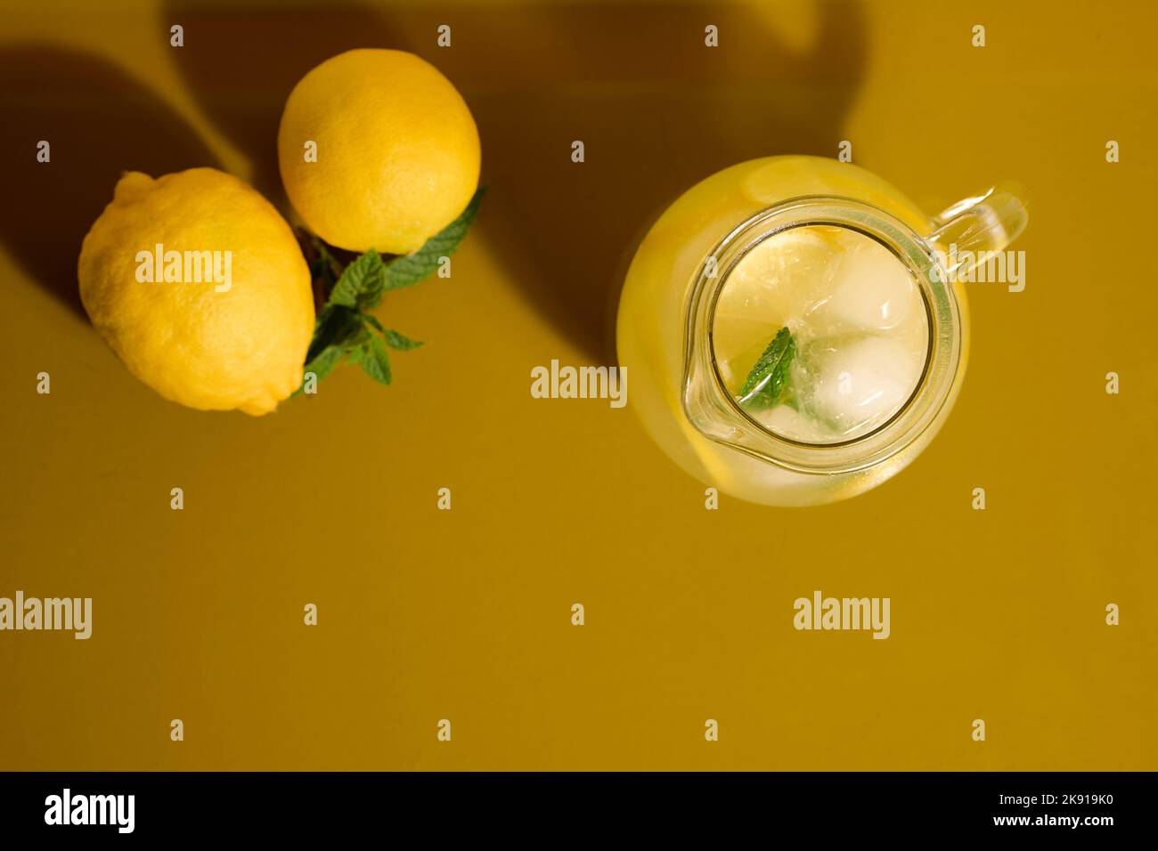 Limonata fresca su sfondo giallo con limoni e menta Foto Stock