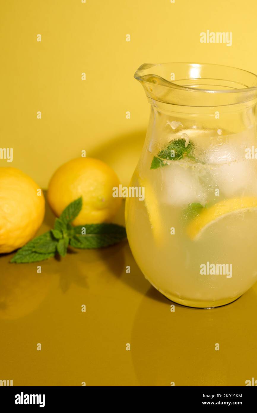 Limonata fresca su sfondo giallo con limoni e menta Foto Stock