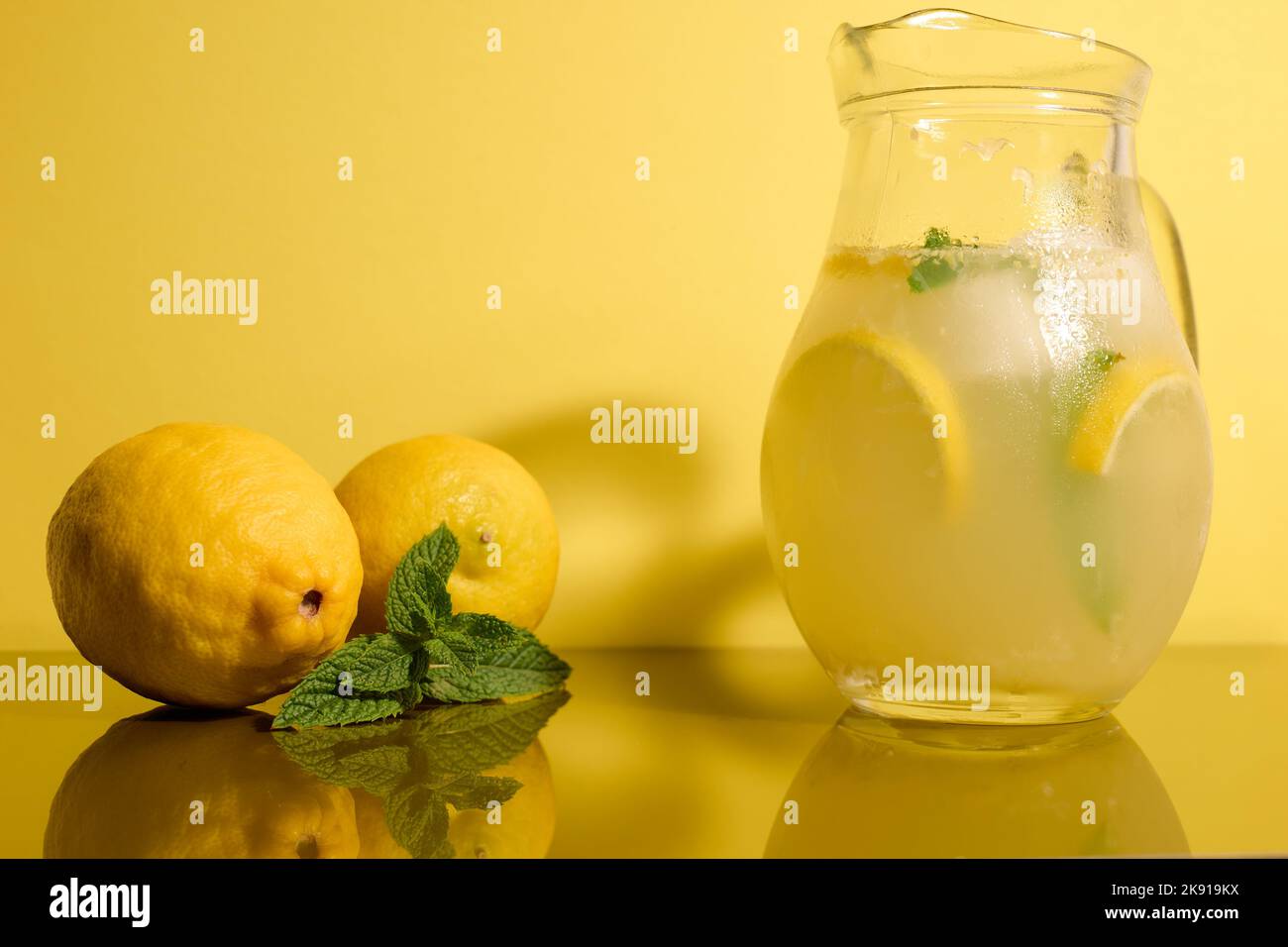 Limonata fresca su sfondo giallo con limoni e menta Foto Stock