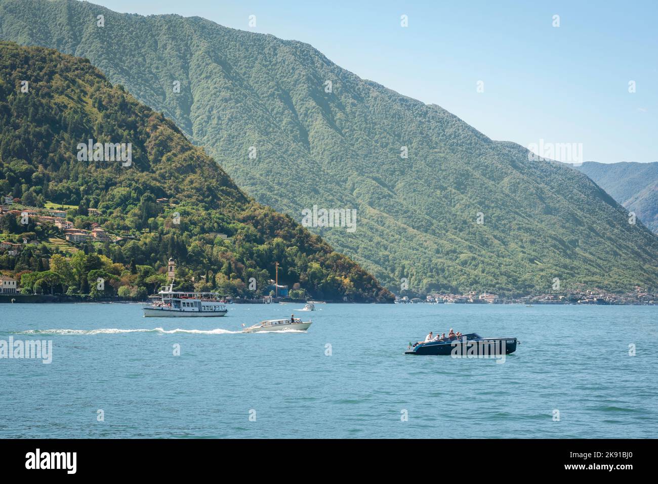 Lago d'Italia, vista in estate di una varietà di barche sul lago di Como che mostrano le colline panoramiche della Lombardia che si elevano dal bordo del lago, Lago di Como, Italia Foto Stock