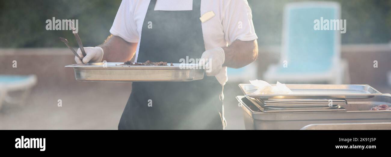 Lo chef trasporta il pasto cotto, costruzione in metallo per friggere il cibo, fare grill, pic-nic all'aperto Foto Stock