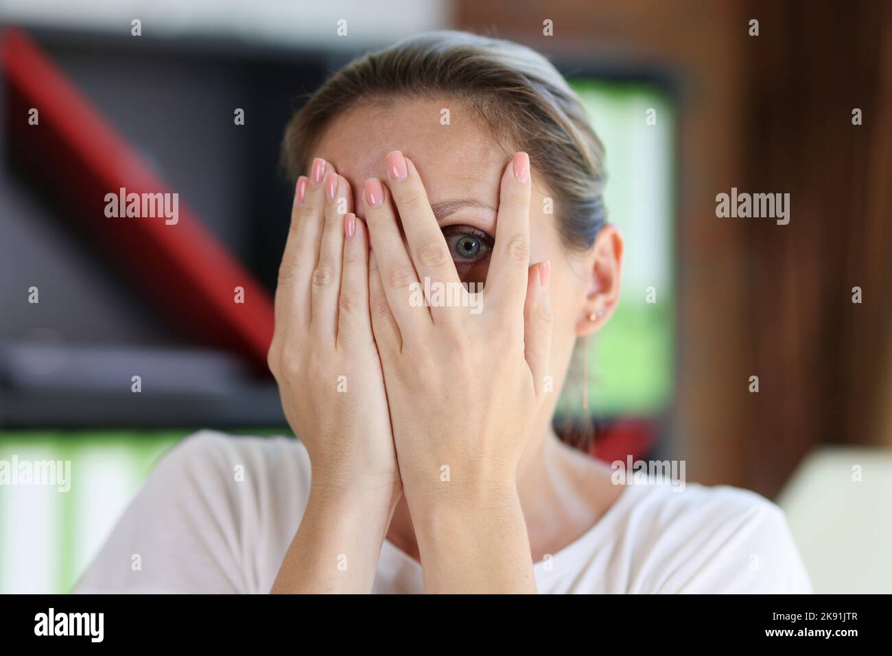 Donna scioccata o spaventata che guarda attraverso le dita Foto Stock