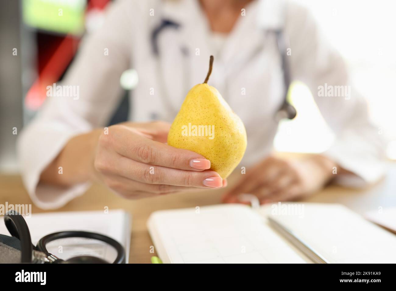 Medico che tiene in mano la pera gialla matura Foto Stock