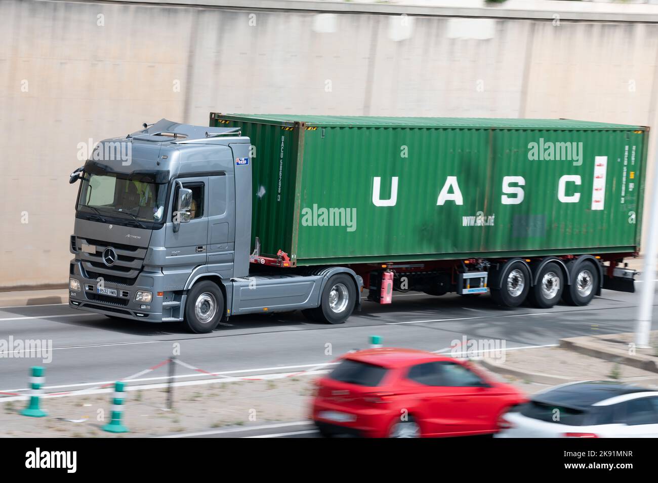 Autocarro Mercedes Actros grigio che carica un rimorchio container verde lungo la Ronda Litoral di Barcellona Foto Stock