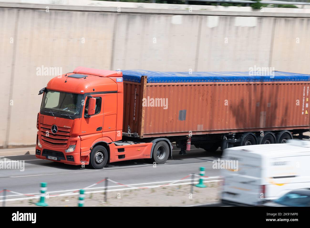 Camion Mercedes Actros rosso che carica un rimorchio container rosso lungo la Ronda Litoral a Barcellona Foto Stock
