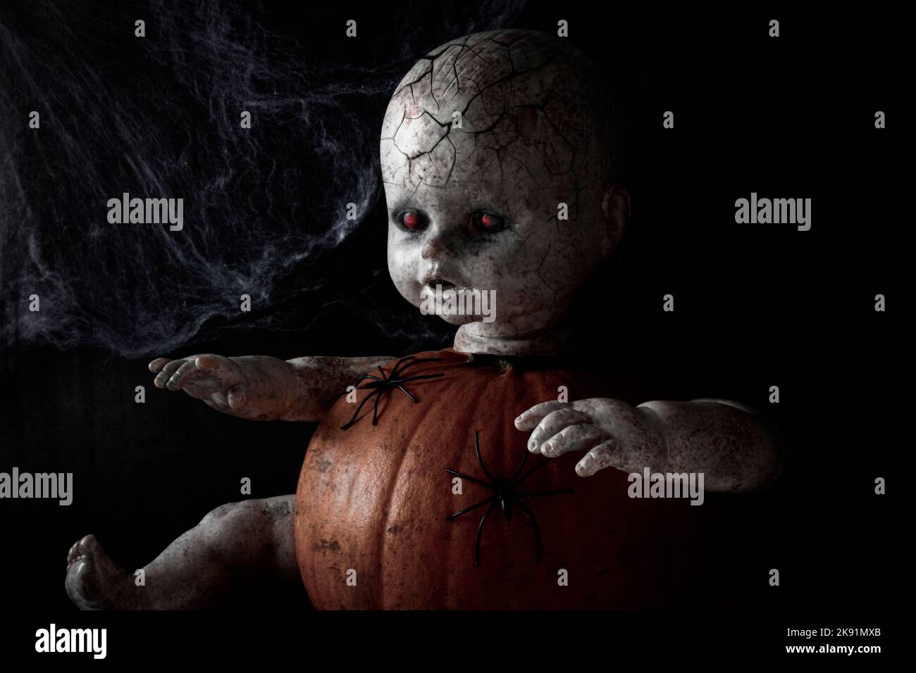 Ritratto di bambola zombie. Sfolgorante volto di bambola con occhi rossi luminosi e pelle zombie su sfondo nero. Concetto di Halloween. Foto Stock