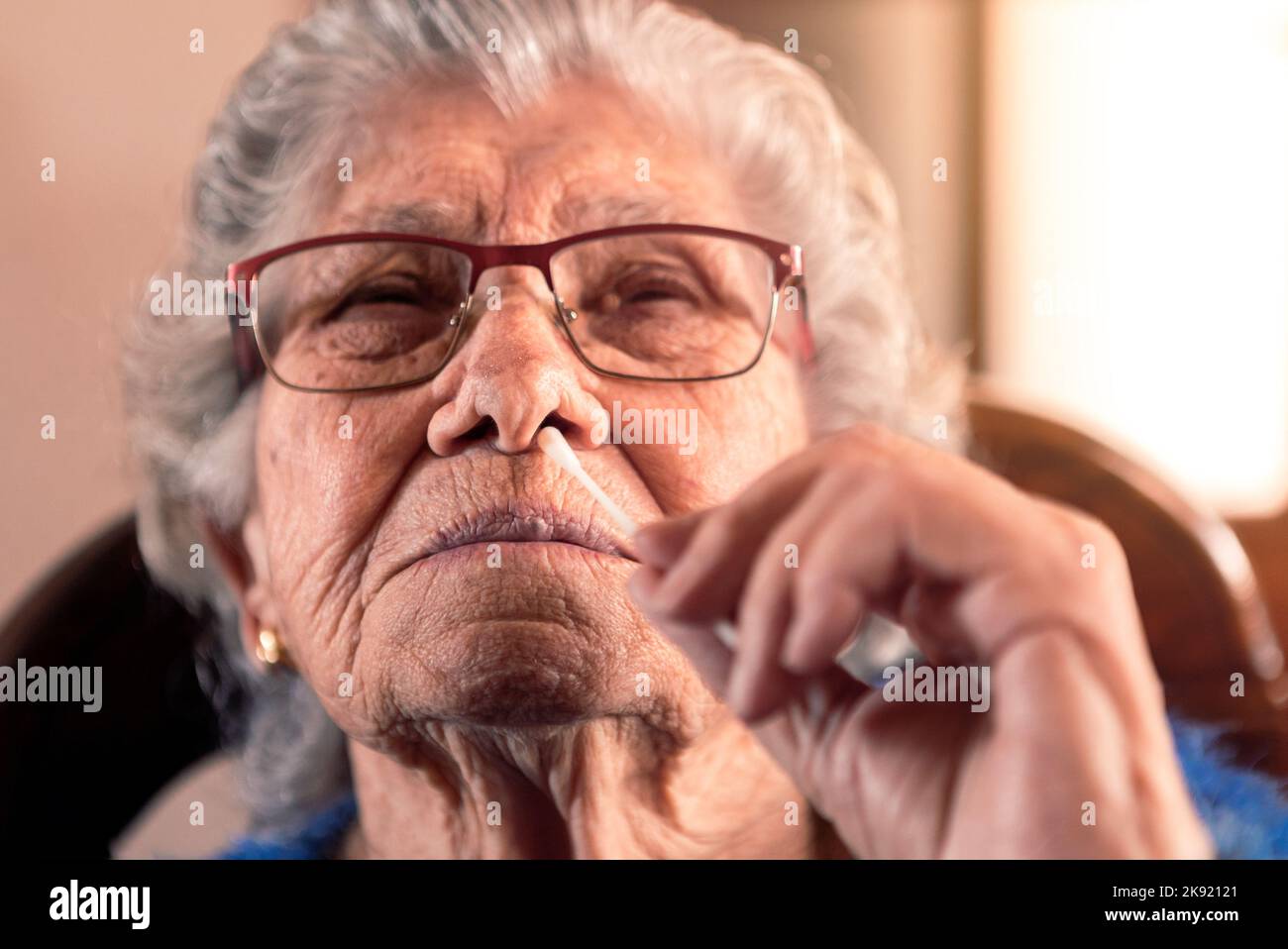Ritratto di vecchia donna che prende un auto swabbing home test per Covid19 con antigene kit. Nonna caucasica introdurre il bastone nasale per controllare l'infezione Foto Stock