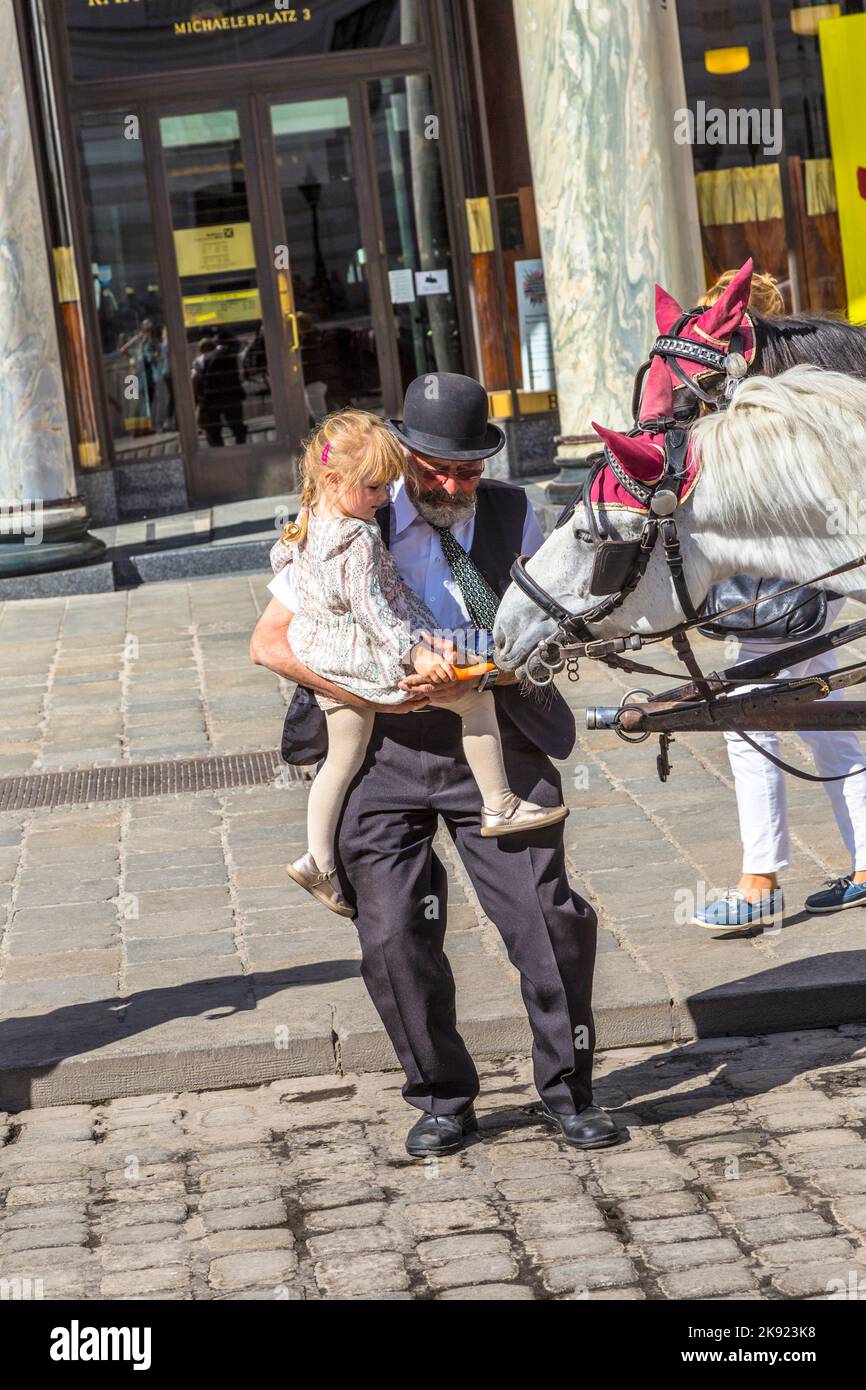 VIENNA, AUSTRIA - Apr 27, 2015: coachman di equitazione tradizionale a vienna aiuta una giovane ragazza a nutrire i cavalli. Il numero di cavalli è l Foto Stock