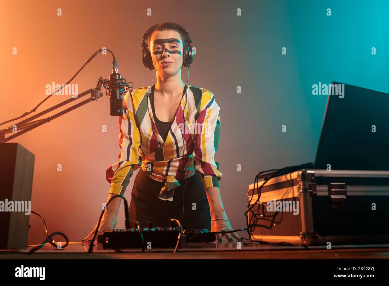 Disco jockey con pazzo make up avere partito per mixare dischi e canzoni techno ai tavoli da gioco in studio. Uso del mixer per eseguire con apparecchiature audio e strumenti stereo, elettronica. Foto Stock