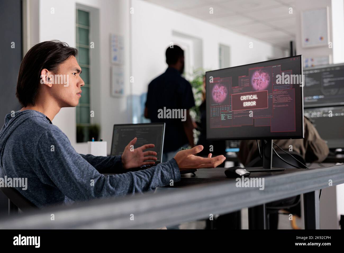 Lo sviluppatore Web non conosce il gesto mentre il server Web ha violato, guardando l'errore critico sullo schermo del computer in ufficio IT. Ingegnere che cerca di risolvere il problema di hacking, la sicurezza del firewall. Foto Stock