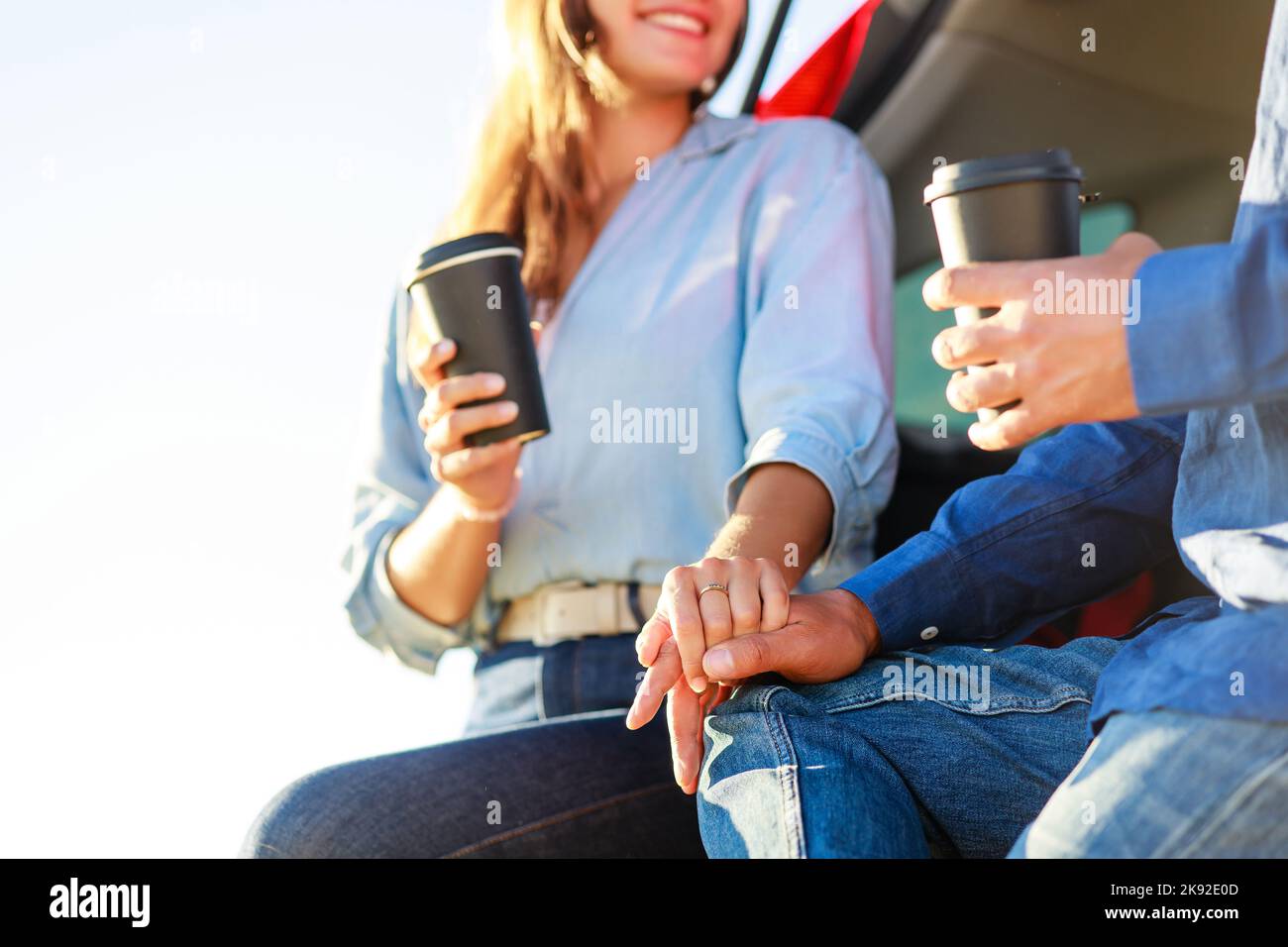 Giovane coppia uomo e donna che viaggiano insieme in auto nuova avendo sosta per bere caffè in un campo di grano al tramonto Foto Stock