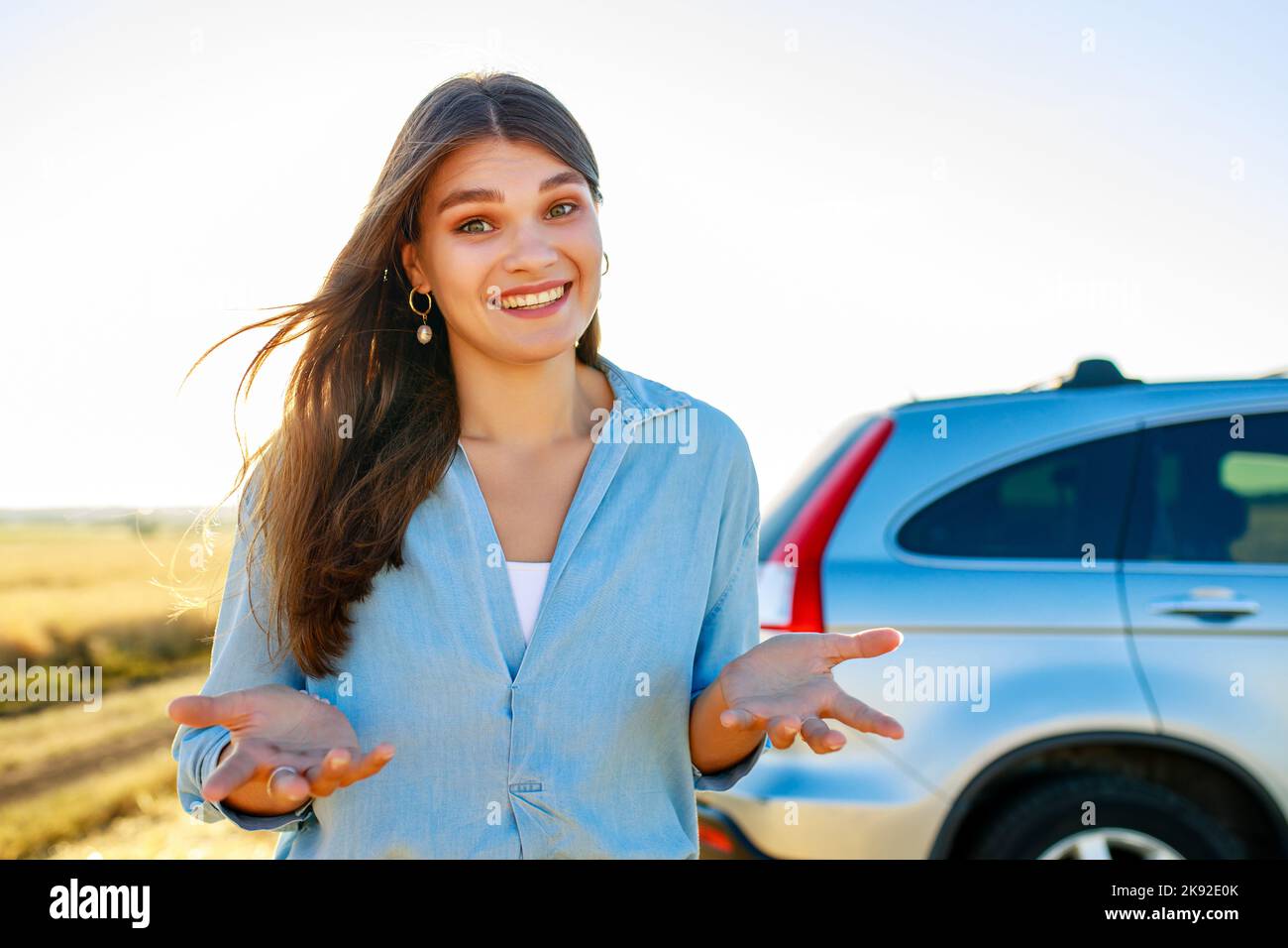 la giovane donna è in piedi con un'espressione colpevole davanti ad un'automobile in un campo Foto Stock