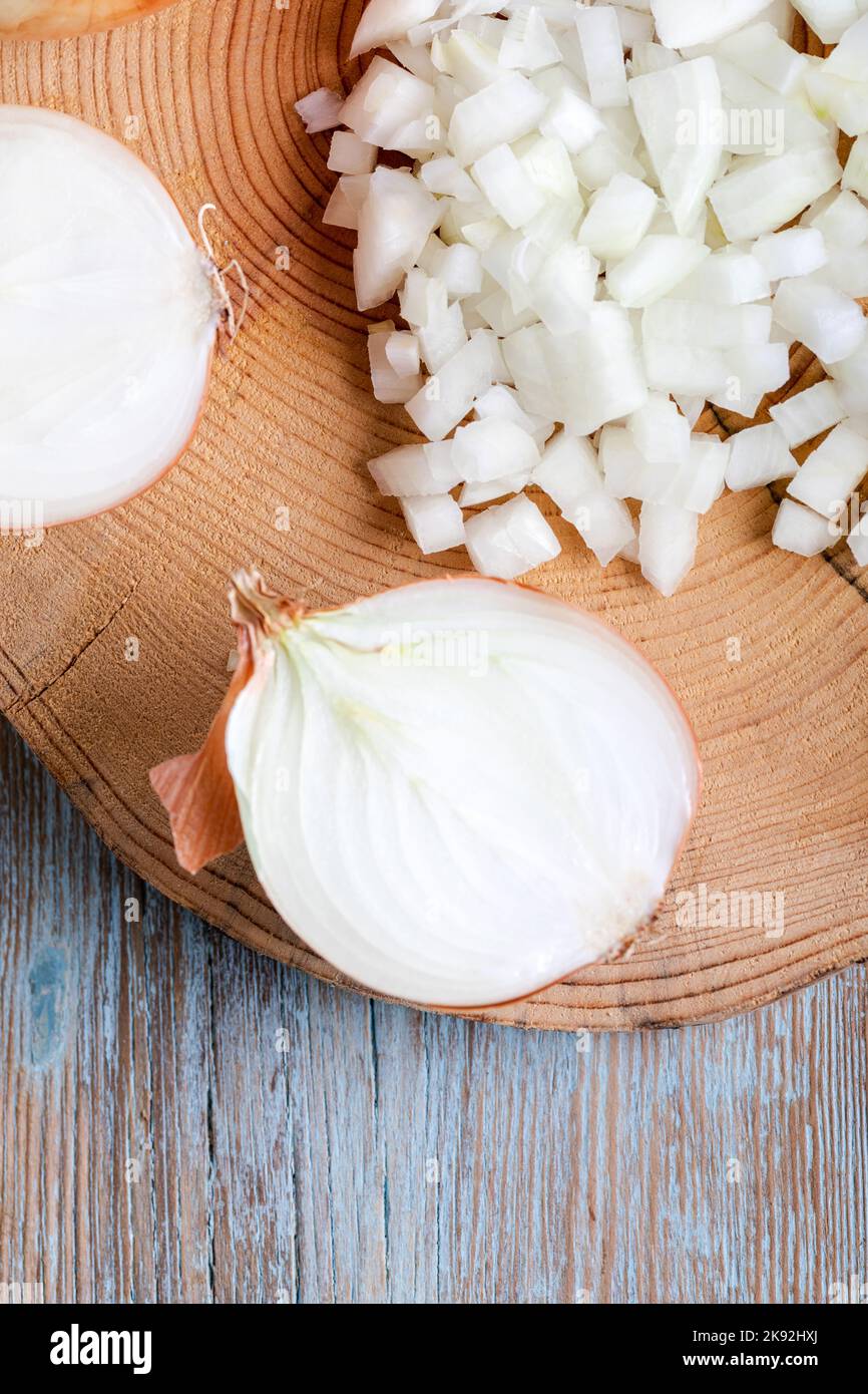 cipolle tagliate a metà e tagliate su un vecchio asse di legno Foto Stock