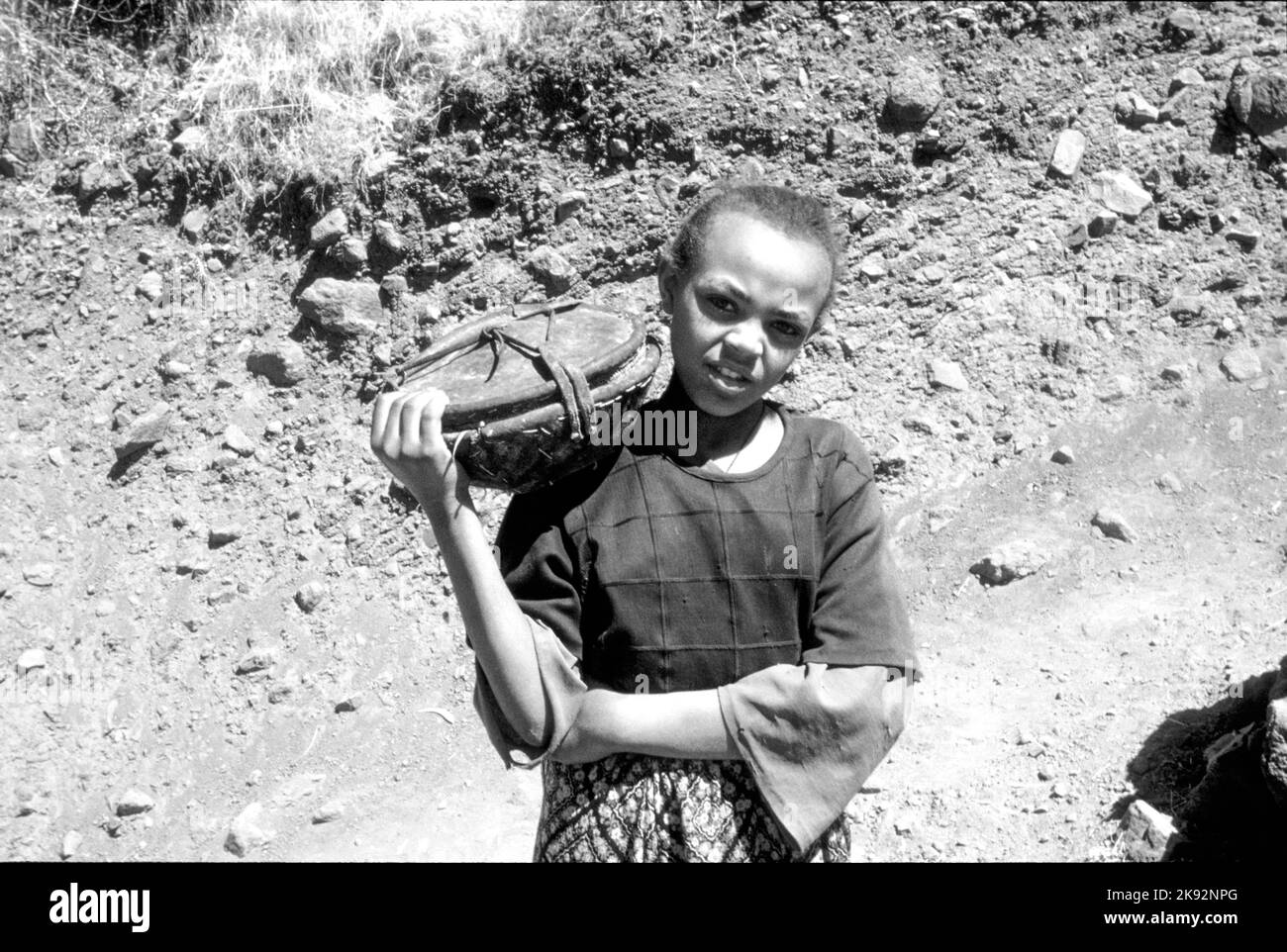 Axum, Etiopia - 1 luglio 1998: La ragazza di fattoria non identificata porta il cibo a suo padre che lavora sul campo in Axum, Etiopia. Foto Stock