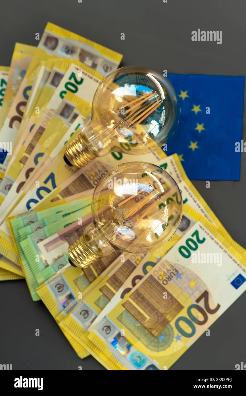 Costo dell'elettricità. Lampadine set e bollette in euro e la bandiera dell'UE su uno sfondo grigio.crisi energetica .aumento dei prezzi dell'elettricità.pagamento dell'elettricità Foto Stock