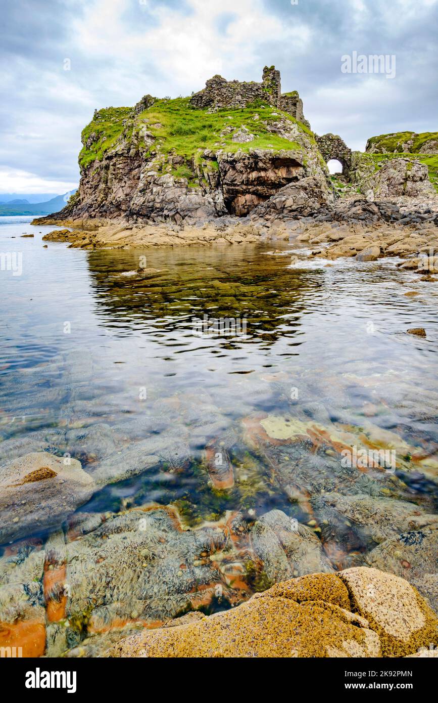 Vicino alle acque tranquille con la bassa marea, a metà estate, resti di un antico, storico castello scozzese, vista, superficie liscia del Loch e molte boul Foto Stock